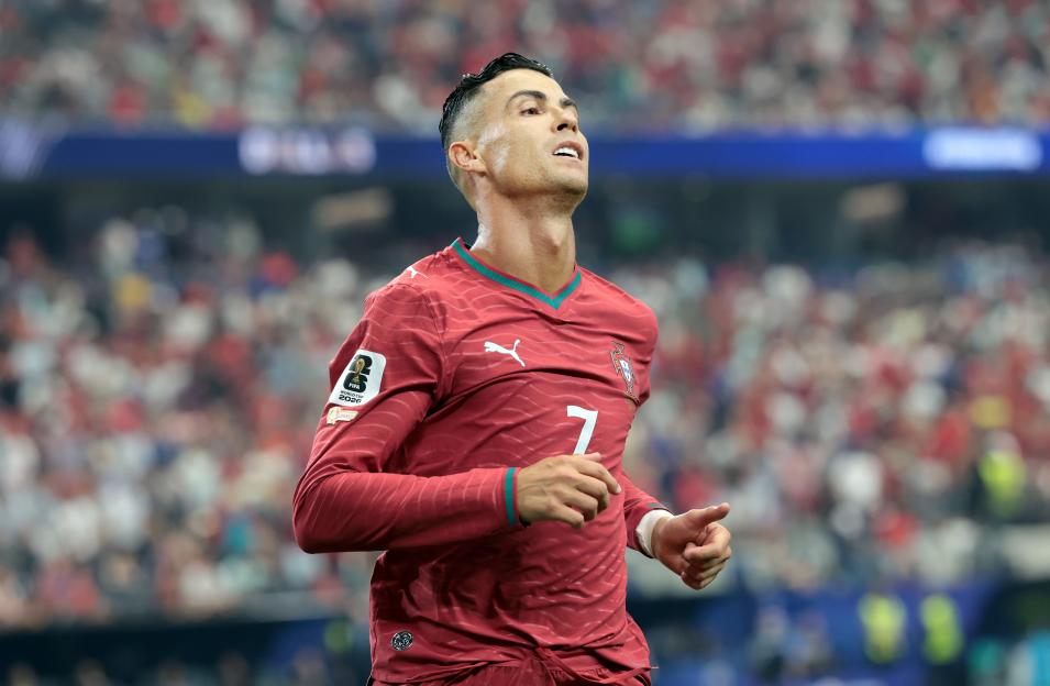 Cristiano Ronaldo in a red jersey looking up during a soccer match.