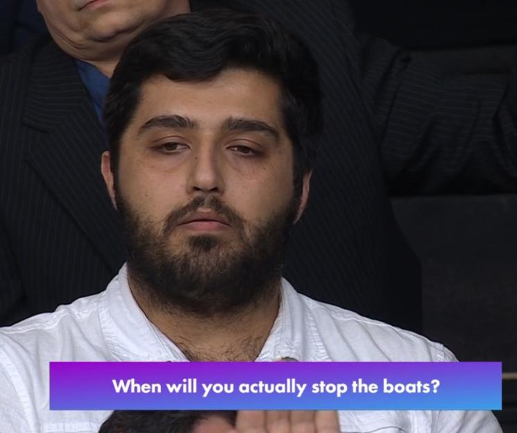 A man in a white shirt and dark beard asks, "When will you actually stop the boats?"