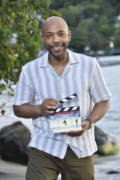 Don Gilet, lead detective in "Death in Paradise", holding a clapperboard.