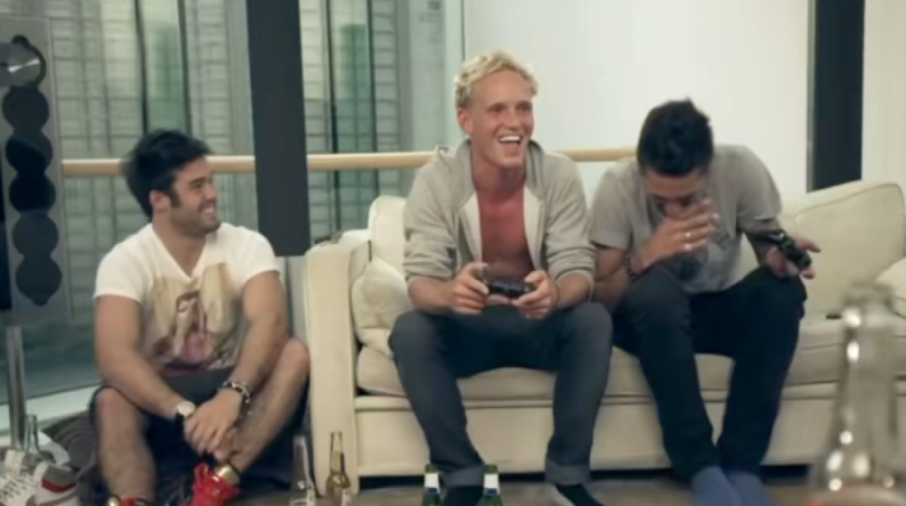 Three men laughing while playing video games.