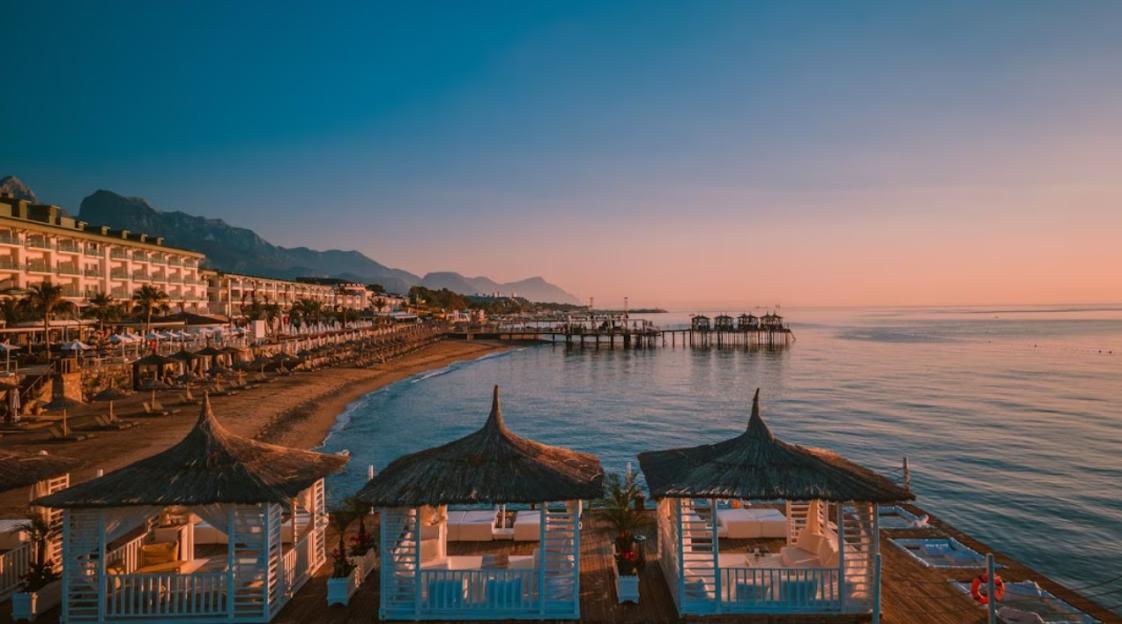 Sunrise view of a beach resort with white wooden cabanas on a pier.