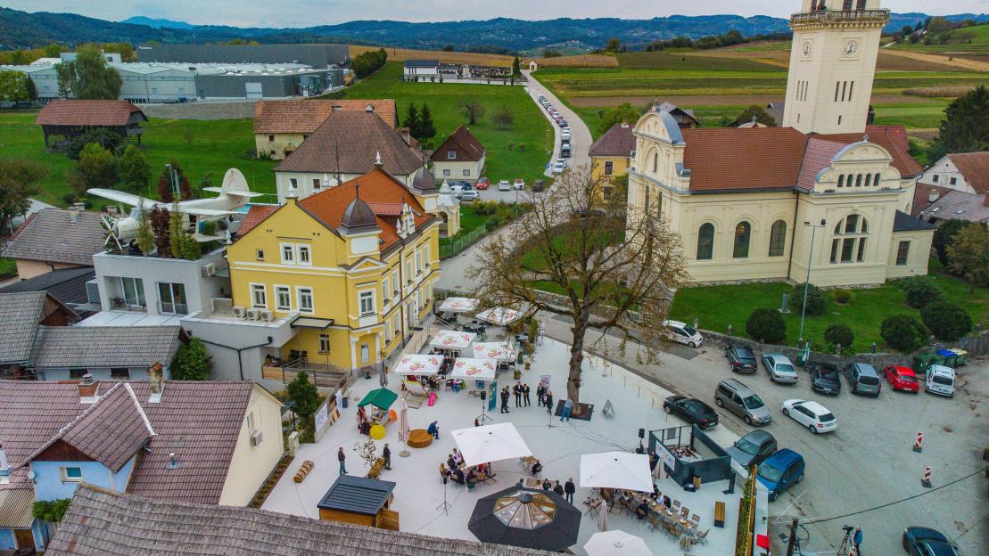 Aerial view of Smarjeta, Slovenia, showing the boutique hotel Dvorec Gregorcic, an old city church, and a town square with a Cvicek fountain.