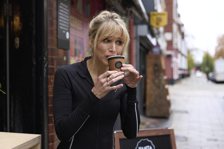 Amanda (Lucy Punch) sips from a coffee cup.