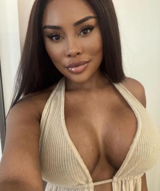A woman with long dark hair, wearing a low-cut ribbed halter top.