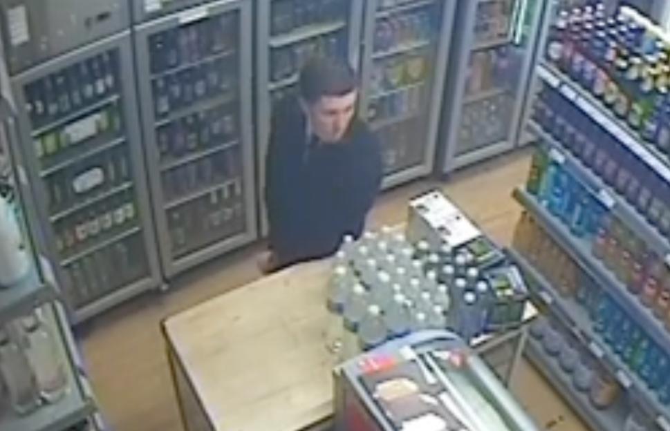Henry Nowak inside a store with drinks refrigerators and shelves of bottled drinks in the background.