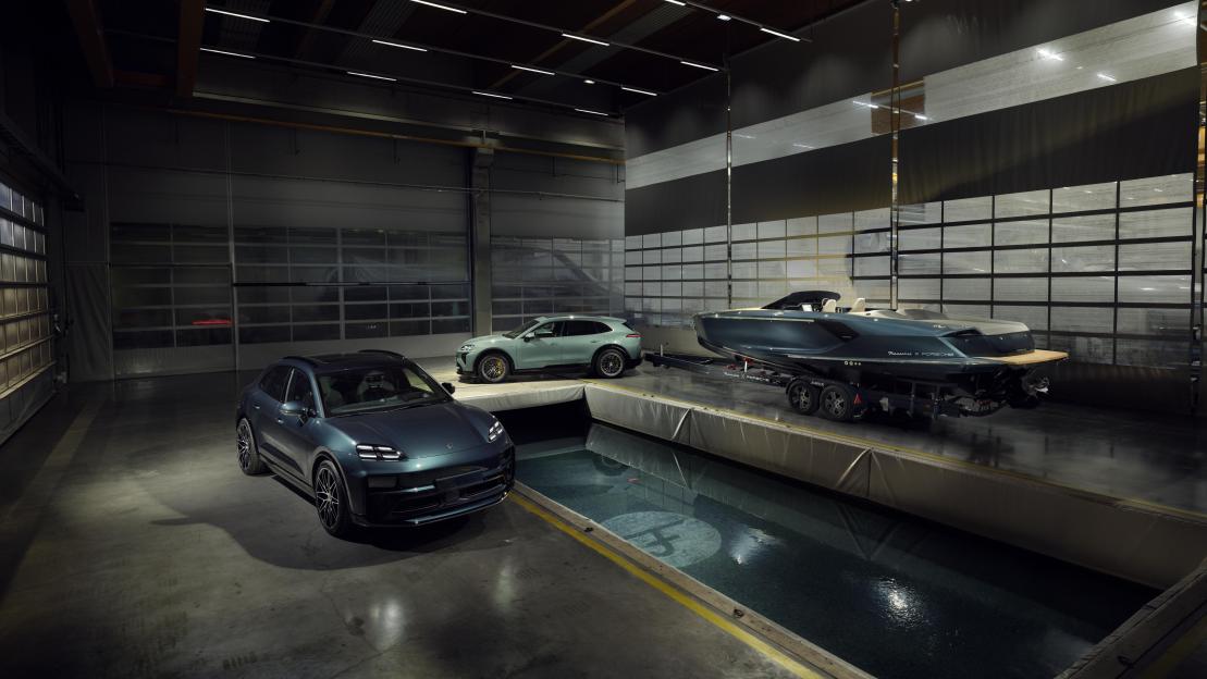 Two Porsche Macan electric vehicles in a garage with a speedboat.