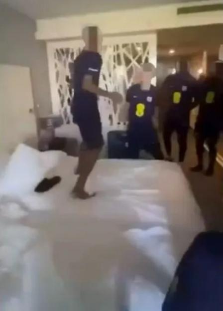 England U16 football players in a hotel room, one jumping on the bed while others watch, appearing to be in a brawl.
