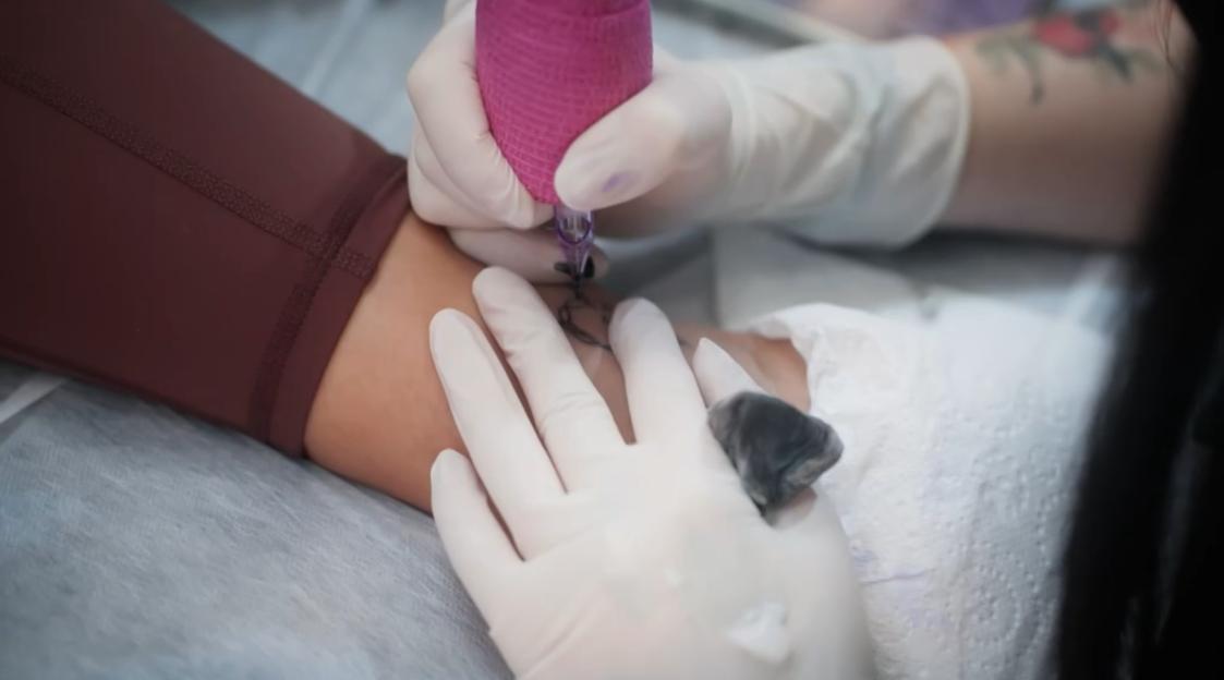 A close-up shot of a person getting a tattoo on their arm.
