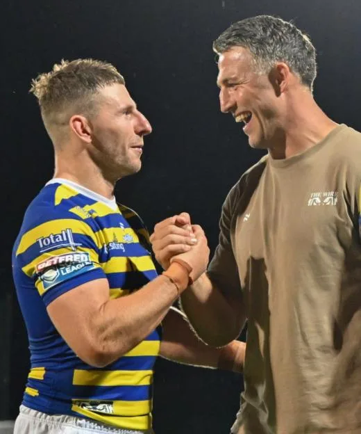Warrington Wolves player George Williams shaking hands and laughing with coach Sam Burgess.