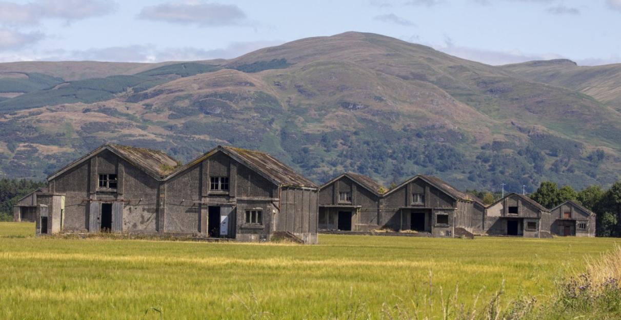 WW1 naval bomb depots in a field with mountains in the background.
