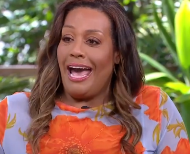 A woman with brown hair, light brown skin, and an orange and white flowered blouse, looking surprised with her mouth open.