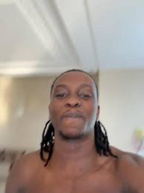 A man with dreadlocks looking forward.
