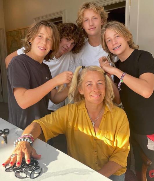 Sarah Beeny with her four sons, two of whom are putting her blonde hair into pigtails.