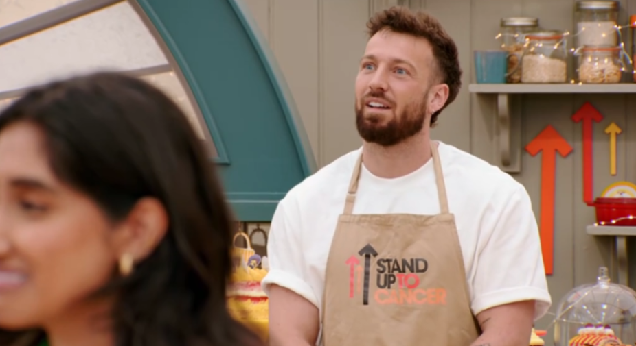 A man in a "Stand Up To Cancer" apron talking to a woman.