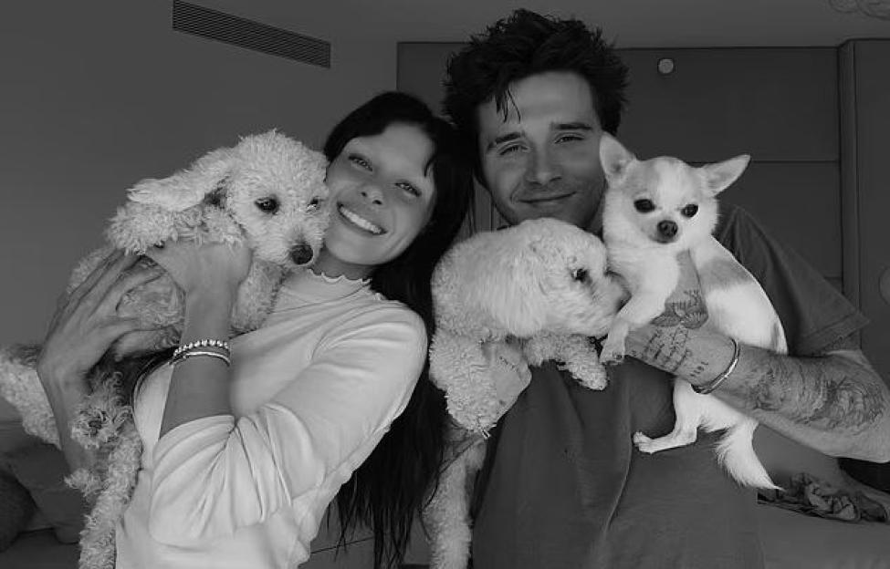 Nicola Peltz and Brooklyn Beckham smiling while holding their dogs.