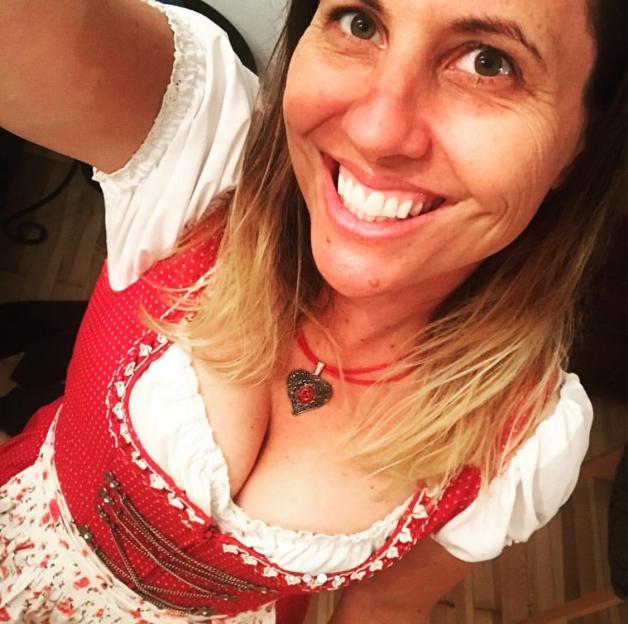Woman smiling while wearing a dirndl and heart-shaped necklace.