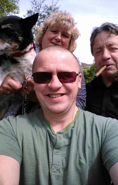 Three people, one holding a dog, posing for a selfie outdoors.