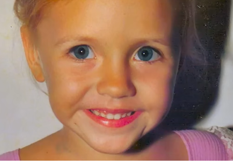 Close-up of a smiling young girl with blue eyes.