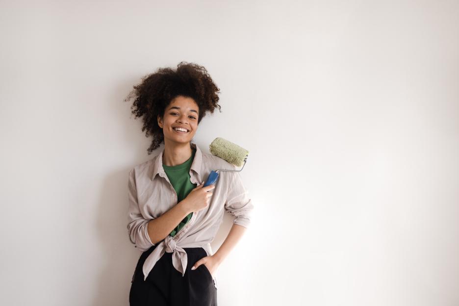 Smiling young African American woman holding a paint roller.