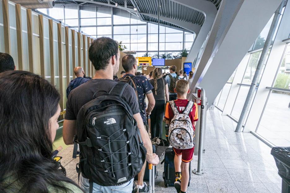 People waiting in a long queue at Eindhoven Airport.