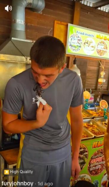 A boy attempts to eat a scorpion.