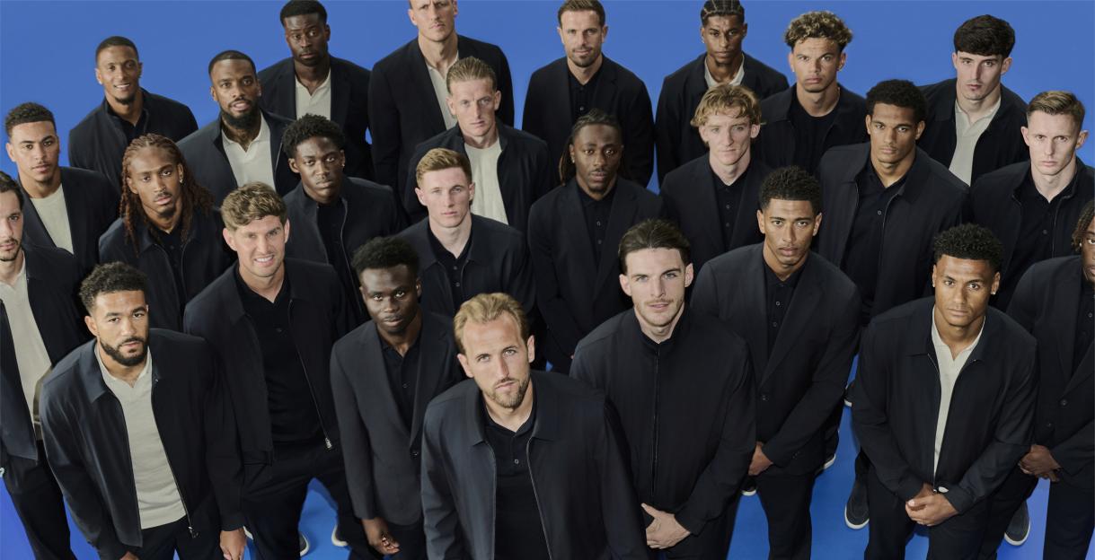 Collage of over twenty male soccer players wearing dark jackets and standing against a blue background.