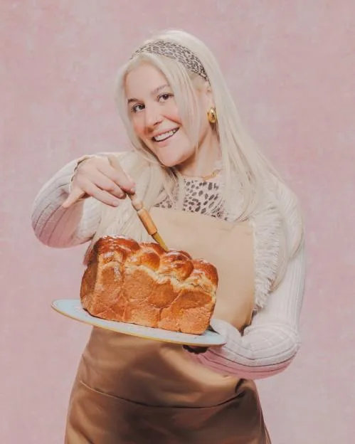 Clara, a contestant on The Great British Bake Off, holding a plate with a braided loaf of bread.