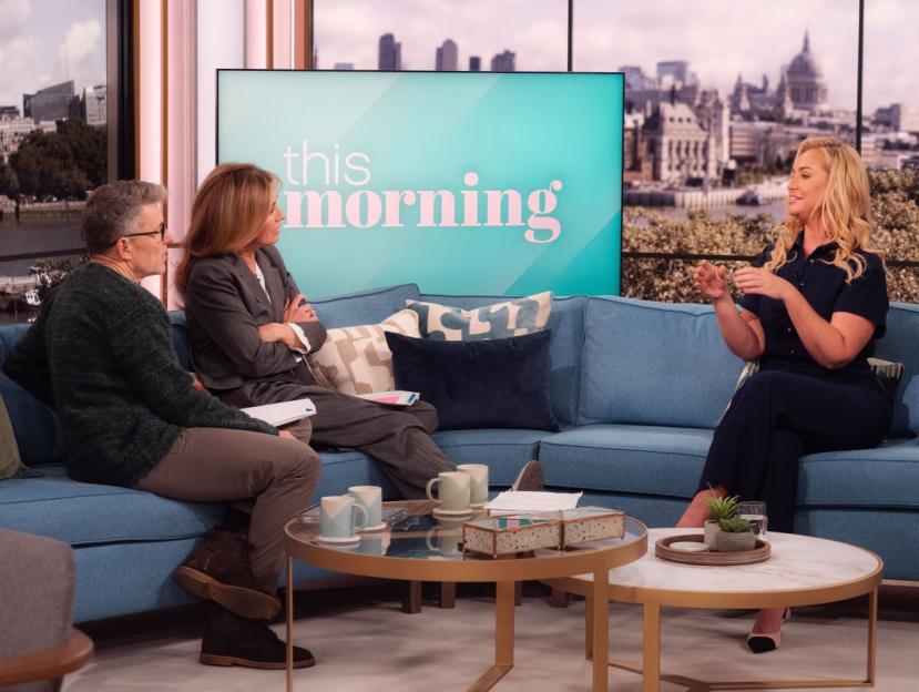 Three people on a blue sofa in front of a "This Morning" screen.
