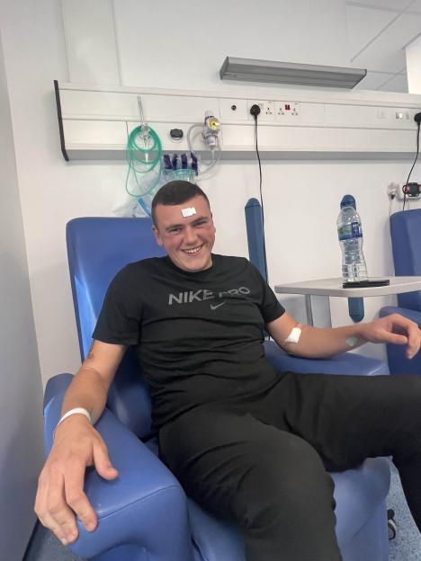Jake Watts, sitting in a hospital chair, smiling after being diagnosed with a cancerous bone tumor.