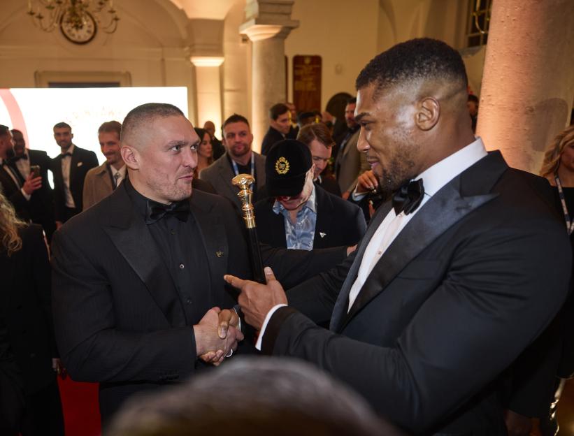 Anthony Joshua and Oleksandr Usyk shake hands at an awards event.