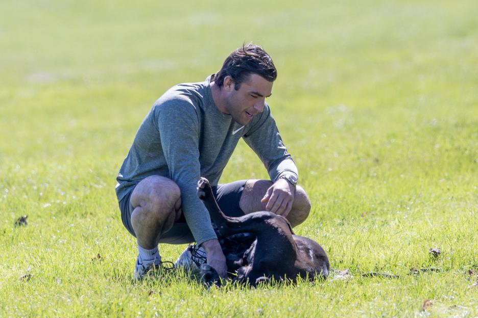 Jack Fincham crouches in a field and pets his dog, Elvis.