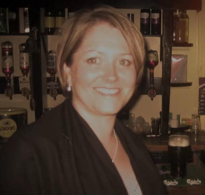 Diana Garbutt smiling in a bar with a pint of beer in front of her.