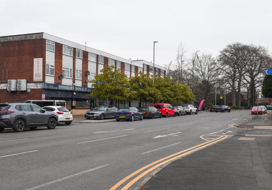 A street view of Burnage, Manchester, featuring a row of parked cars alongside a building housing "Tondori Royale Restaurant & Takeaway."