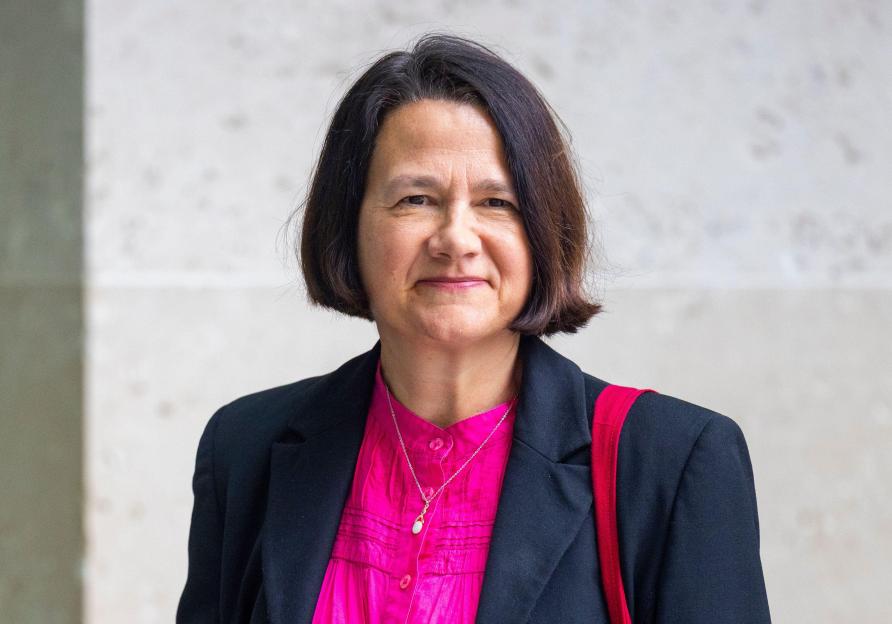 Catherine West, Labour MP, wearing a black blazer over a bright pink blouse and a silver necklace.