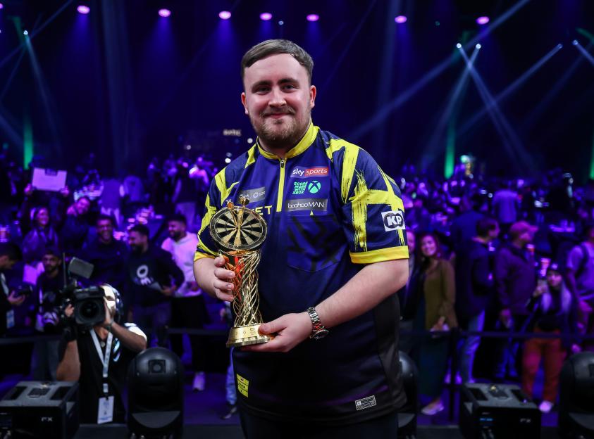 Luke Littler holding the Saudi Darts Masters trophy.