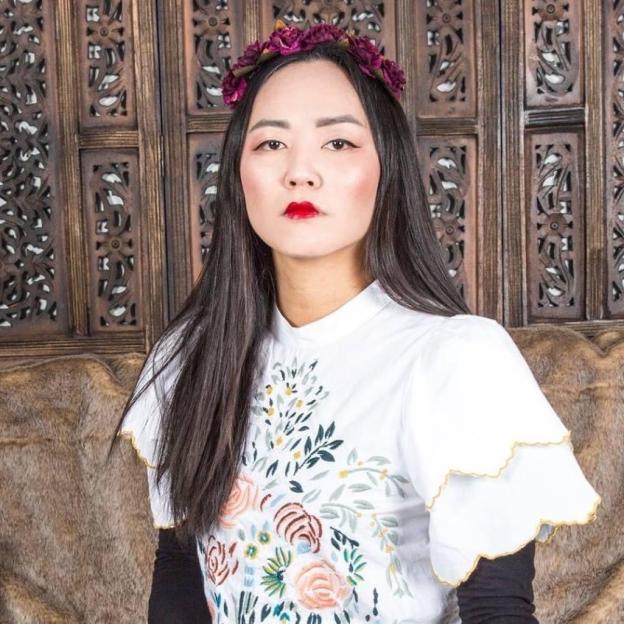 Rino Oh, an Epstein survivor, wearing a flower crown and an embroidered shirt.