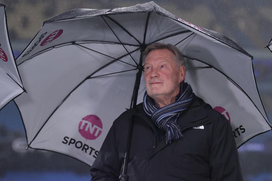 TNT Sports pundit Glenn Hoddle holding an umbrella during a football match.