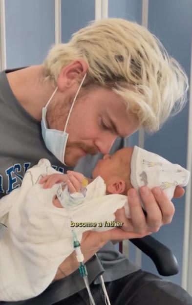 Tommy Fury holding his newborn baby.