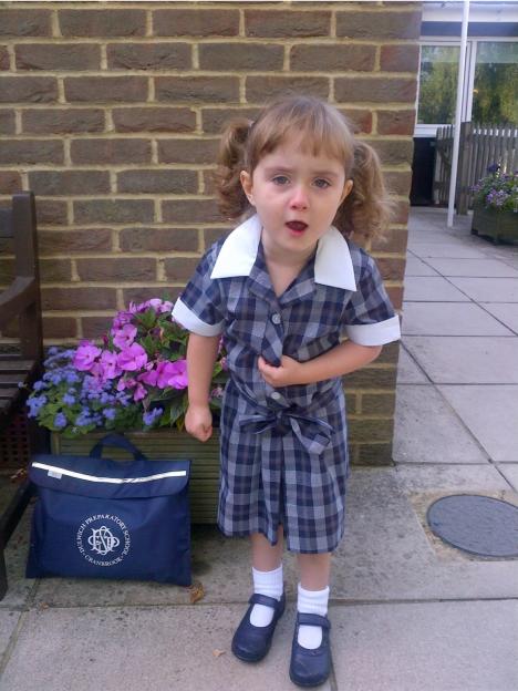 Young girl in school uniform with a school bag.