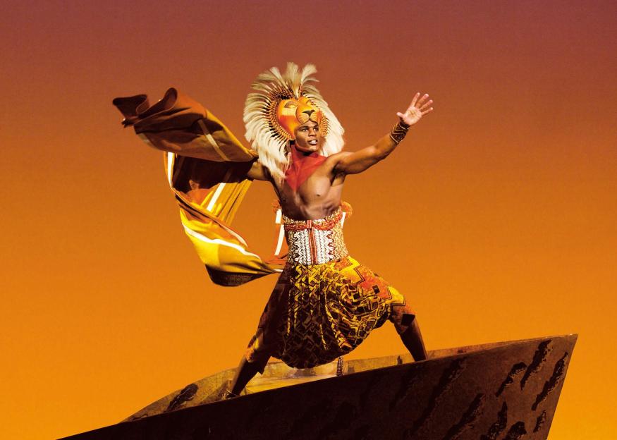 A performer in a lion mask and elaborate costume from The Lion King musical.