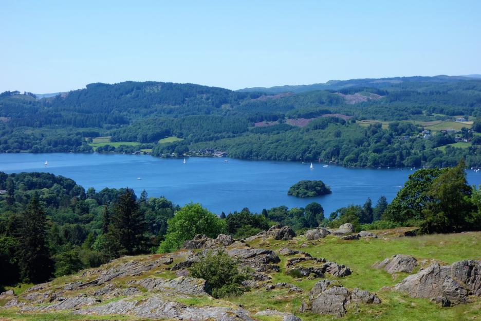 Scenic view of Lake Windermere in the English Lake District with surrounding hills and forests.