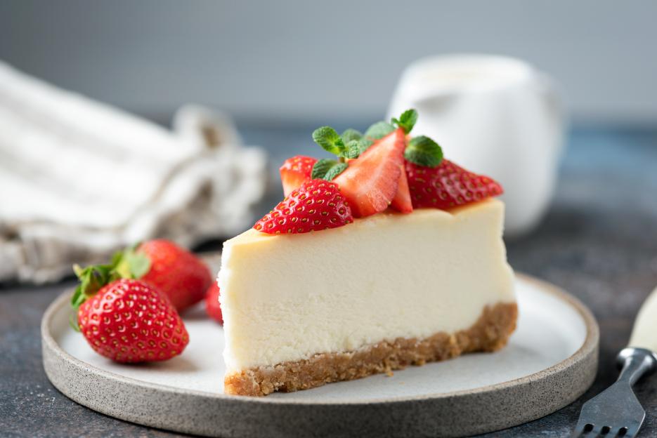 Slice of strawberry cheesecake with graham cracker crust on a plate.