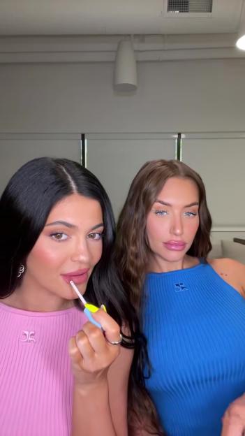 Kylie Jenner applying lip gloss while standing next to Stassie Karanikolaou.