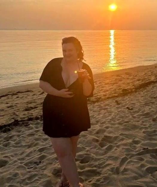 A woman on a beach in Thailand at sunset, with text saying she was at her biggest at 16 stone/size 18.