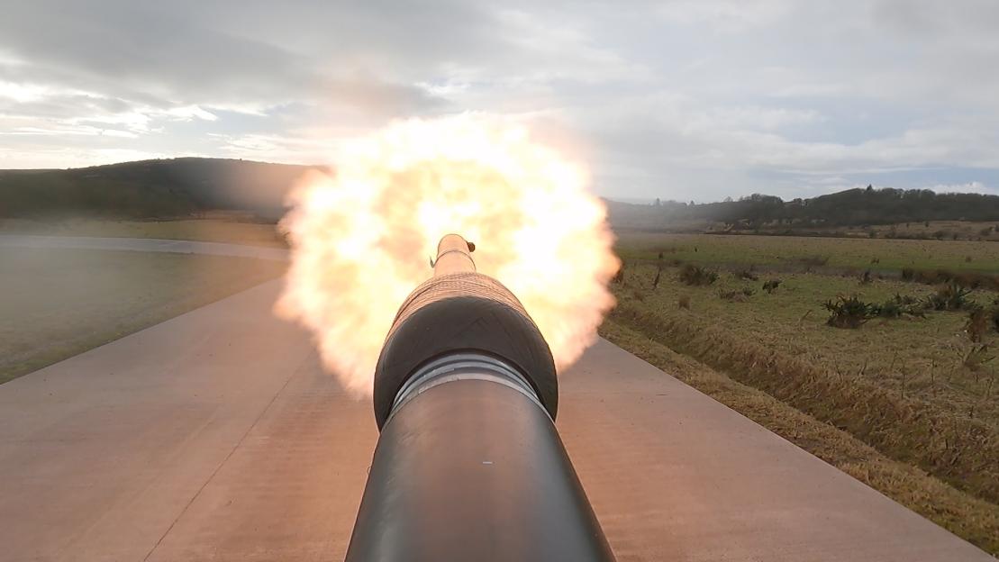 A cannon fires, showing a burst of flame from the muzzle.