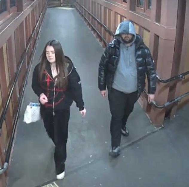 Two individuals walking down a ramp with railings.