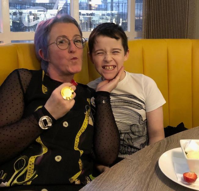 Sarah Lundy making a funny face while her son Charlie grins next to her in a restaurant.