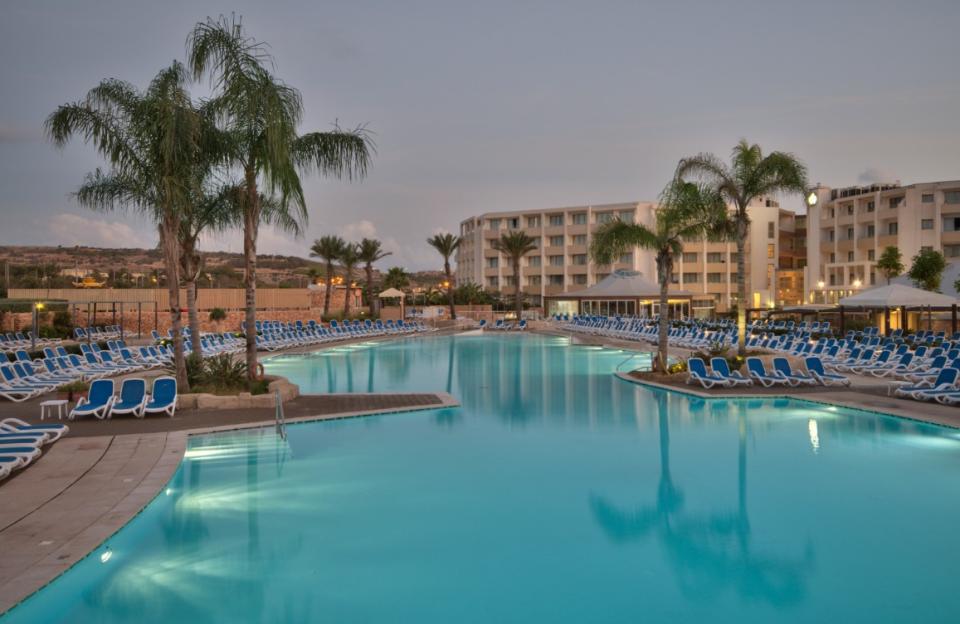 A resort swimming pool and hotel buildings at dusk.