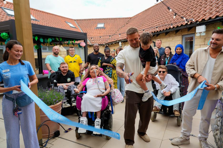 Alex Bowen cutting a ribbon at a children's hospice courtyard opening.