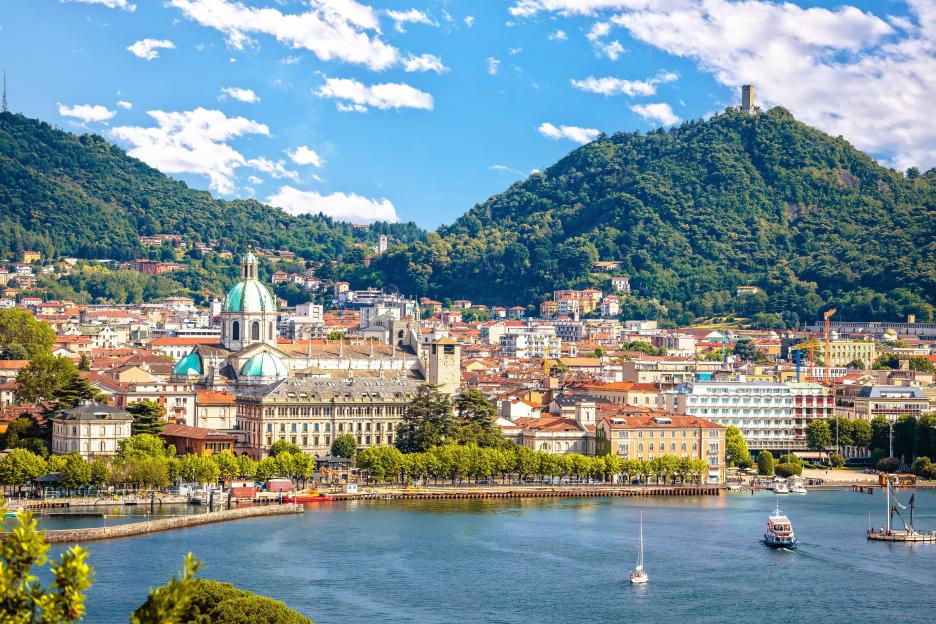 Scenic view of Como, Italy, with historic buildings, a lake, and mountains.